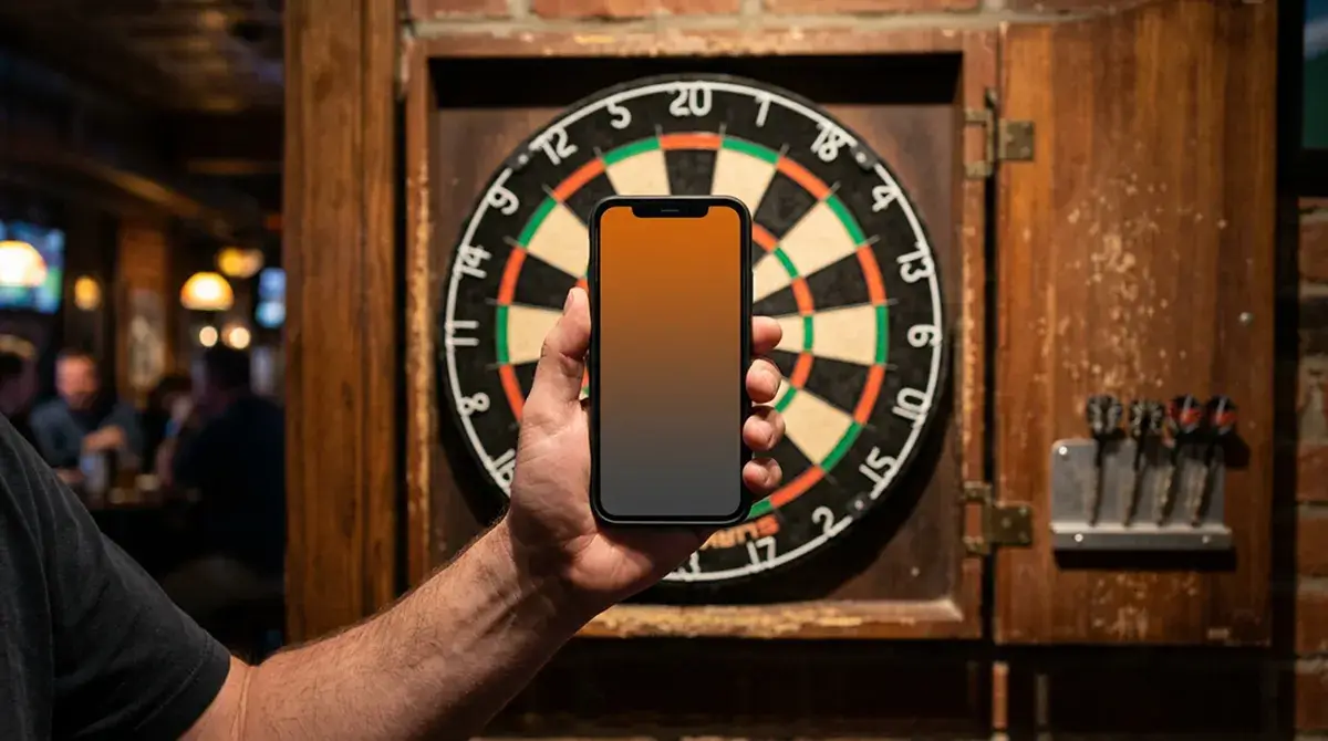 Hand hält ein Smartphone vor einer Dartscheibe in einer Sport-Bar-Umgebung
