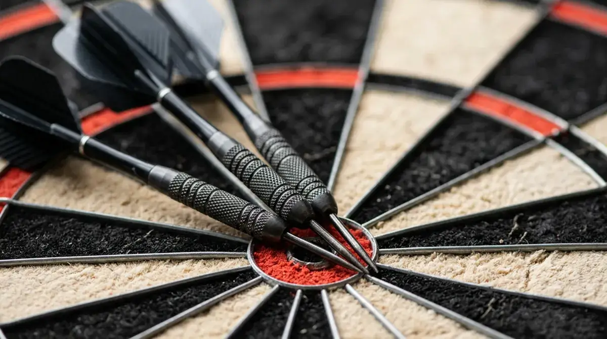 Drei Steeldarts mit dunklen Tungsten-Barrels im Triple-20-Segment einer Sisal-Dartscheibe in Nahaufnahme